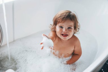 Cute little girl washing in the bat at home. Top view.