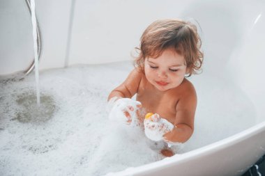 Evdeki yarasada yıkanan tatlı küçük kız. Üst görünüm.