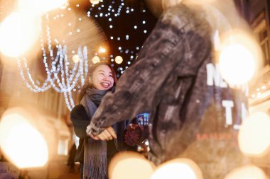 Çelenklerin yapay ışıklandırması. Mutlu, çok ırklı bir çift şehrin dışında yeni yılı kutluyor..