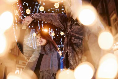 Çelenklerin yapay ışıklandırması. Mutlu, çok ırklı bir çift şehrin dışında yeni yılı kutluyor..