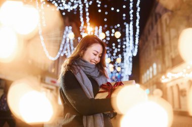 Hediye kutusuyla. Şehirdeki sevimli ve mutlu Asyalı genç bayan yeni yılı kutluyor..