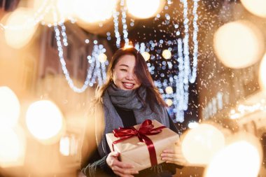 Hediye kutusuyla. Şehirdeki sevimli ve mutlu Asyalı genç bayan yeni yılı kutluyor..