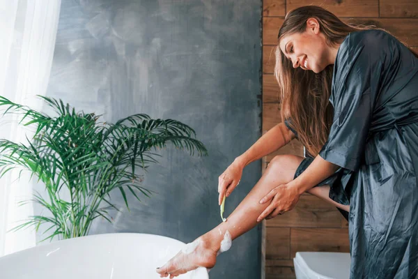 Güzel genç bayanın evde banyoda boş zamanı var. Bacaklarını tıraş eder..