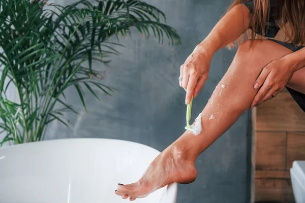 Güzel genç bayanın evde banyoda boş zamanı var. Bacaklarını tıraş eder..