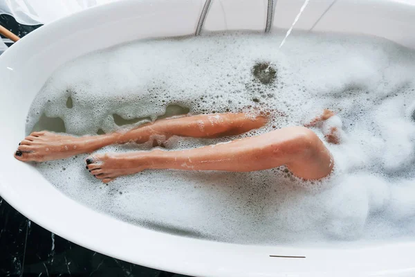 Bacakların parçacık görünümü. Güzel genç bayanın evde, banyoda boş vakti var..