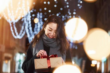 Hediye kutusuyla. Şehirdeki sevimli ve mutlu Asyalı genç bayan yeni yılı kutluyor..