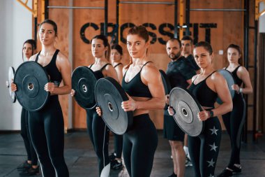 Ağırlık tutuyor. Bir grup genç sporcu spor salonunda iç içe geçiyor..