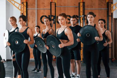 Ağırlık tutuyor. Bir grup genç sporcu spor salonunda iç içe geçiyor..