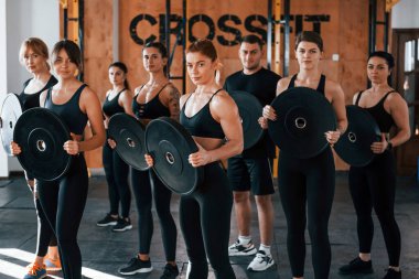 Ağırlık tutuyor. Bir grup genç sporcu spor salonunda iç içe geçiyor..