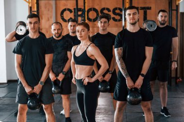 Kamera için poz vermek. Bir grup genç sporcu spor salonunda iç içe geçiyor..