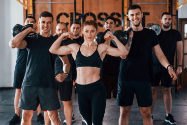 Kamera için poz vermek. Bir grup genç sporcu spor salonunda iç içe geçiyor..