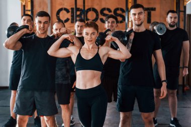 Kamera için poz vermek. Bir grup genç sporcu spor salonunda iç içe geçiyor..