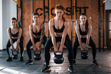 Ağırlık kaldırma. Bir grup genç sporcu spor salonunda iç içe geçiyor..