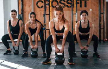 Ağırlık kaldırma. Bir grup genç sporcu spor salonunda iç içe geçiyor..