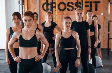 Kamera için poz vermek. Bir grup genç sporcu spor salonunda iç içe geçiyor..