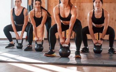 Ağırlık kullanarak. Bir grup genç sporcu spor salonunda iç içe geçiyor..
