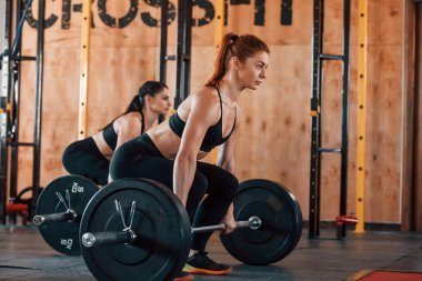 Halteri kaldırıyorum. Bir grup genç sporcu spor salonunda iç içe geçiyor..