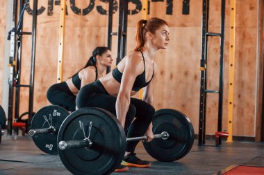 Halteri kaldırıyorum. Bir grup genç sporcu spor salonunda iç içe geçiyor..