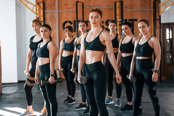 Kamera için poz vermek. Bir grup genç sporcu spor salonunda iç içe geçiyor..