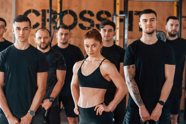 Kamera için poz vermek. Bir grup genç sporcu spor salonunda iç içe geçiyor..