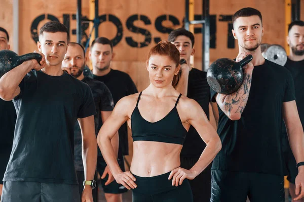 Kamera için poz vermek. Bir grup genç sporcu spor salonunda iç içe geçiyor..