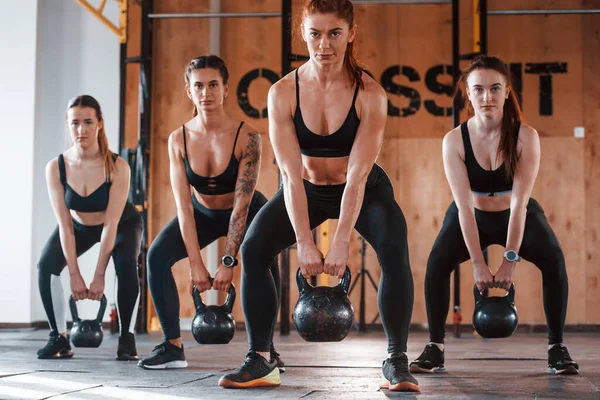 Ağırlık kullanarak. Bir grup genç sporcu spor salonunda iç içe geçiyor..