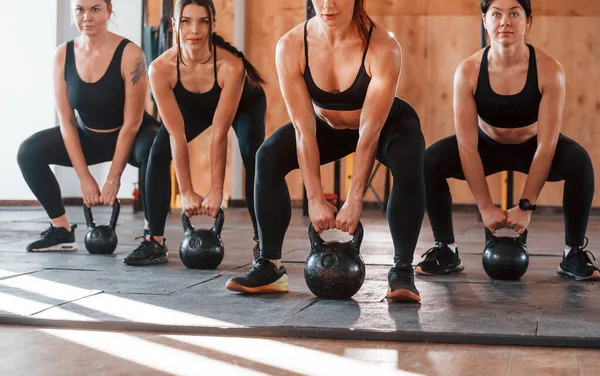 Ağırlık kullanarak. Bir grup genç sporcu spor salonunda iç içe geçiyor..