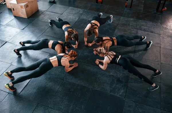 Plank egzersizi. Bir grup genç sporcu spor salonunda iç içe geçiyor..