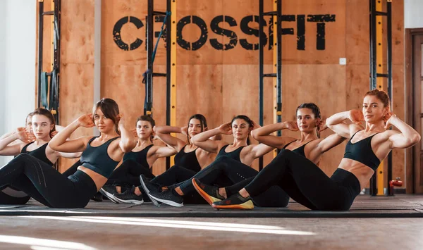 Karın kasları. Bir grup genç sporcu spor salonunda iç içe geçiyor..