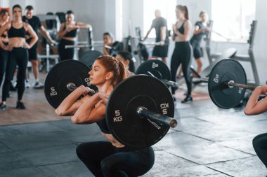 Halteri kaldırıyorum. Bir grup genç sporcu spor salonunda iç içe geçiyor..