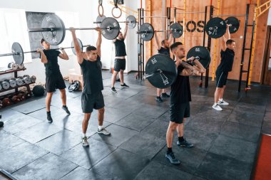 Halterlerle birlikte. Bir grup genç sporcu spor salonunda iç içe geçiyor..