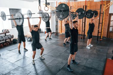 Halterlerle birlikte. Bir grup genç sporcu spor salonunda iç içe geçiyor..