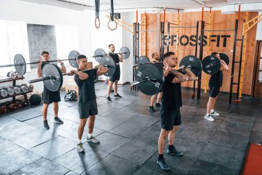 Halterlerle birlikte. Bir grup genç sporcu spor salonunda iç içe geçiyor..