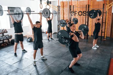 Halterlerle birlikte. Bir grup genç sporcu spor salonunda iç içe geçiyor..