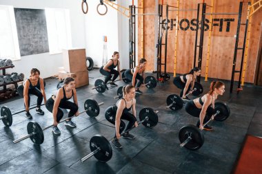 Halterlerle birlikte. Bir grup genç sporcu spor salonunda iç içe geçiyor..