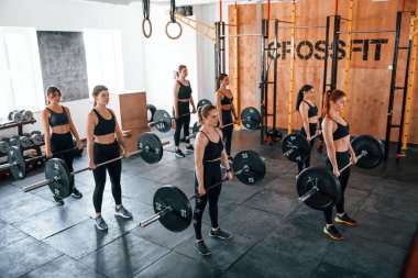 Halterlerle birlikte. Bir grup genç sporcu spor salonunda iç içe geçiyor..