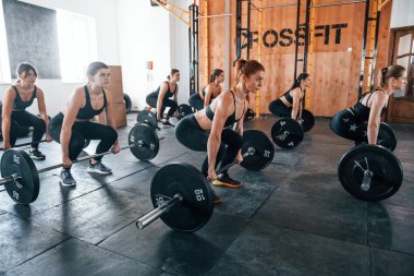 Halterlerle birlikte. Bir grup genç sporcu spor salonunda iç içe geçiyor..