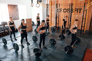 Halterlerle birlikte. Bir grup genç sporcu spor salonunda iç içe geçiyor..