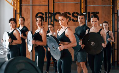 Ağırlık tutuyor. Bir grup genç sporcu spor salonunda iç içe geçiyor..