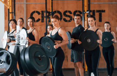 Ağırlık tutuyor. Bir grup genç sporcu spor salonunda iç içe geçiyor..