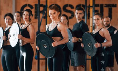 Ağırlık tutuyor. Bir grup genç sporcu spor salonunda iç içe geçiyor..