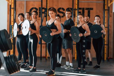 Ağırlık tutuyor. Bir grup genç sporcu spor salonunda iç içe geçiyor..