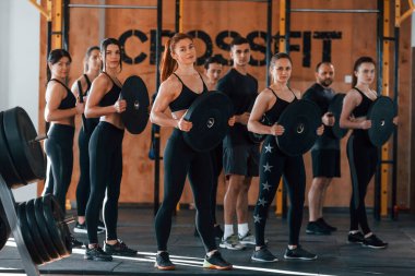 Ağırlık tutuyor. Bir grup genç sporcu spor salonunda iç içe geçiyor..