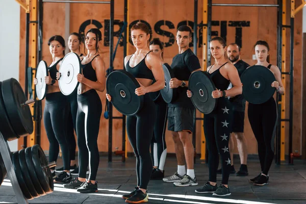 Ağırlık tutuyor. Bir grup genç sporcu spor salonunda iç içe geçiyor..