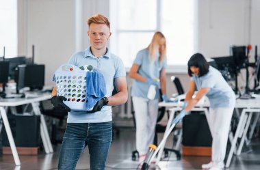 Adam sepeti tutuyor. Bir grup işçi gündüzleri modern ofisi temizliyor..