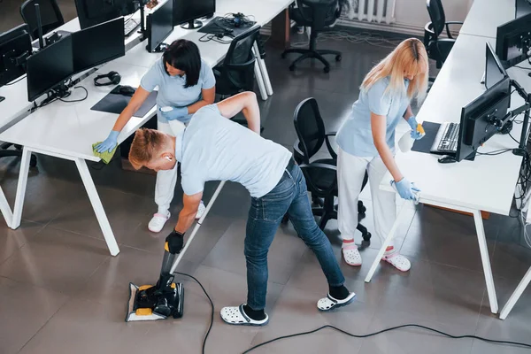 Concentrated at job. Group of workers clean modern office together at daytime.
