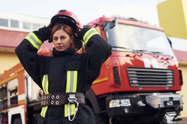 Female firefighter in protective uniform standing near truck.
