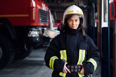 Female firefighter in protective uniform standing near truck.