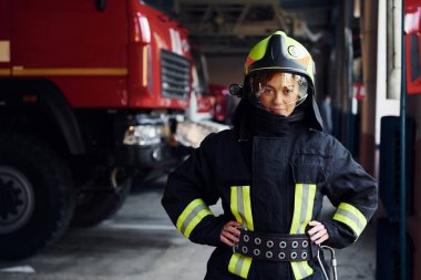Female firefighter in protective uniform standing near truck.