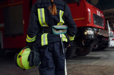 Manzarayı kapat. Koruyucu üniformalı kadın itfaiyeci kamyonun yanında duruyor..